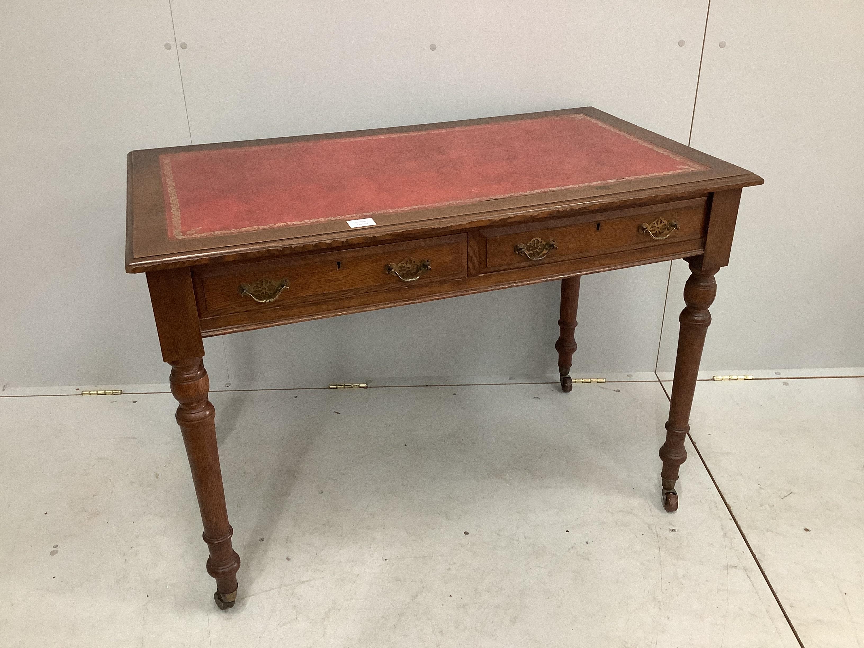 A late Victorian oak two drawer writing table, with red leather inset top, width 106cm, depth 60cm, height 76cm